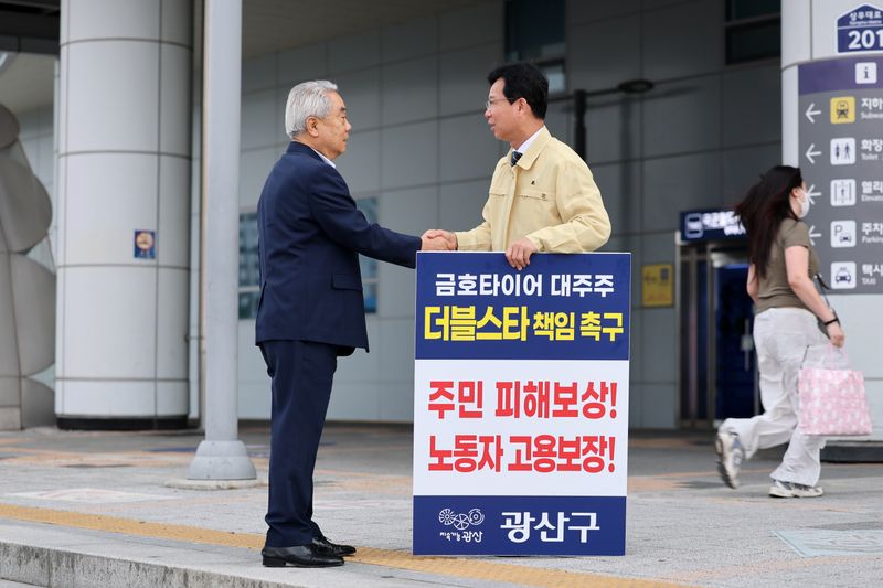 사진설명 = 지난 6월 광주송정역 앞 광장에서 금호타이어 화재와 관련한 더블스타 책임 촉구 1인 시위에 나선 박병규 광산구청장이 길을 지나다 응원을 보낸 시민과 악수를 나누고 있다.