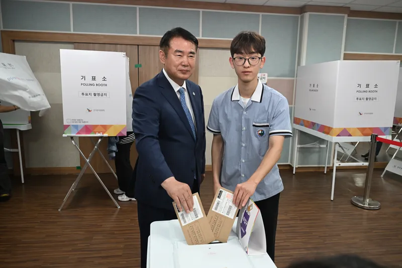 사진설명 = 이정선 광주광역시교육감(왼쪽)이 29일 화정2동 행정복지센터에 마련된 투표소에서 생애 첫 투표자가 된 광덕고 하유성 학생회 부회장(오른쪽)과 투표함에 투표용지를 넣고 있다. / 광주광역시교육청 제공